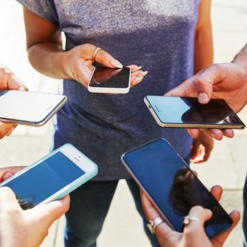 5 friends with smartphones, close up.