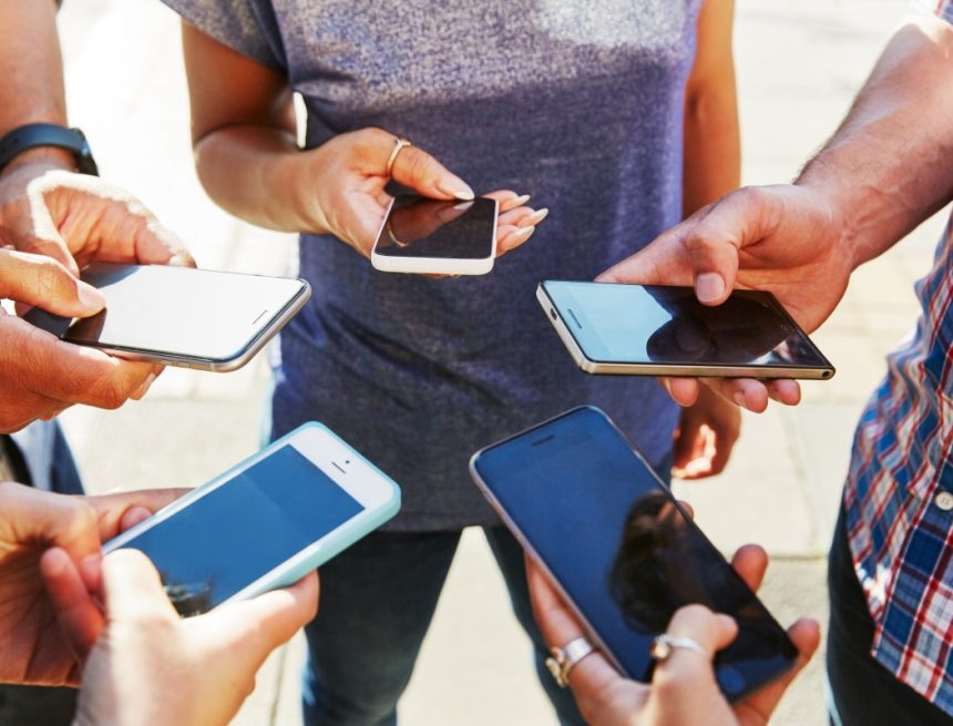 5 friends with smartphones, close up.