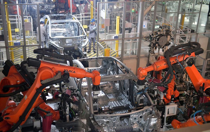 Image of an assembly line where two robots are coordinating the production of an automobile frame.
