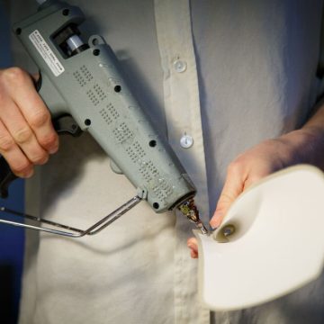 A person holding a grey industrial glue gun.