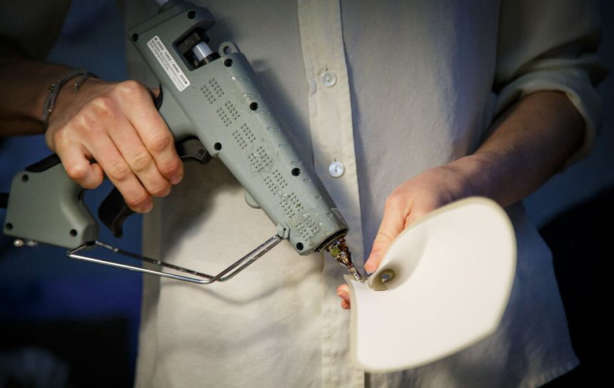A person holding a grey industrial glue gun.