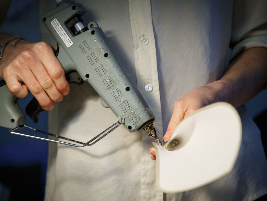 A person holding a grey industrial glue gun.