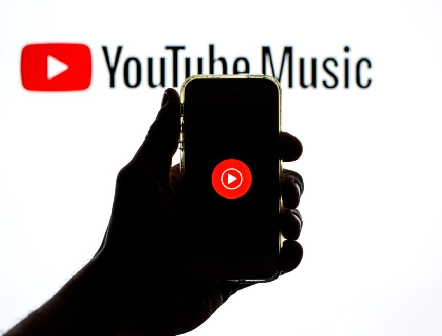 The YouTube Music app seen displayed on a smartphone screen and a YouTube Music logo in the background.