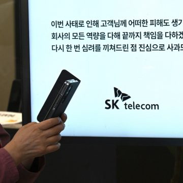 A woman uses her mobile phone while waiting to replace her USIM ship in front of an SK Telecom branch in Seoul on April 28, 2025.