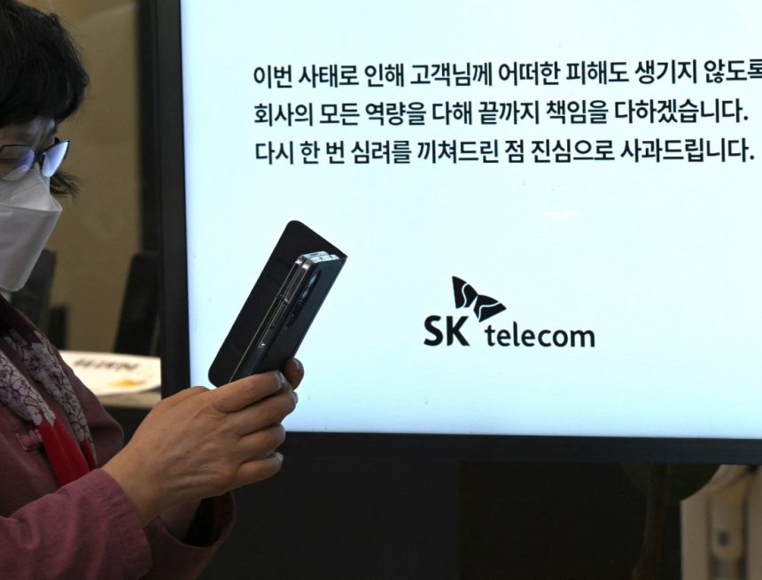 A woman uses her mobile phone while waiting to replace her USIM ship in front of an SK Telecom branch in Seoul on April 28, 2025.