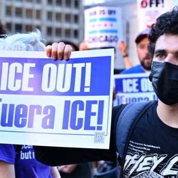 A protestor holds a sign that says "ICE OUT!"