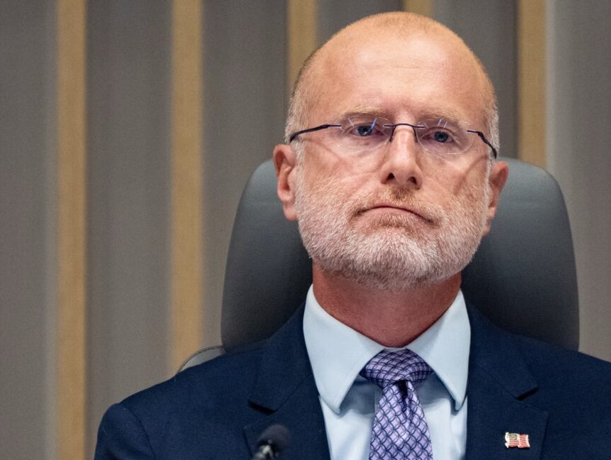 FCC Chairman Brendan Carr sits in front of a microphone during a commission meeting.