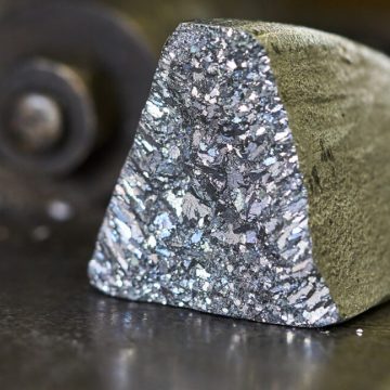 An oddly shaped hunk of metal, with a dull, oxidized color on most surfaces, but one showing freshly exposed material that has a silvery glint.