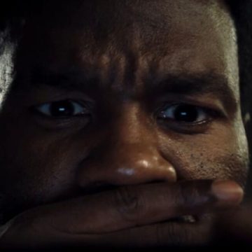 closeup of black man with one hand over his mouth