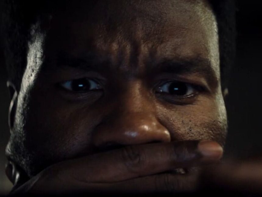 closeup of black man with one hand over his mouth