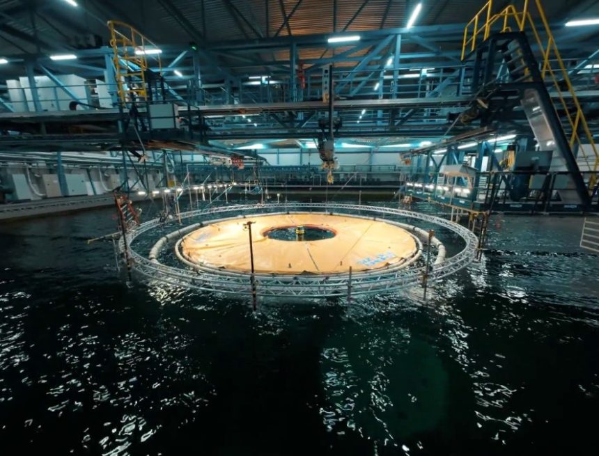 An orange plastic reservoir sits inside a wave tank in a testing facility.