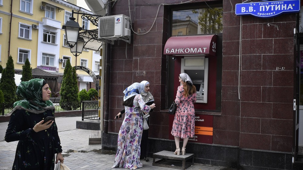 Chechen women wait in front of an ATM machine (automatic teller machine) in downtown Grozny at the Avenue of Vladimir Putin on July 26, 2019. - The main city street, Prospekt Pobedy (Victory Avenue), was named after Russian President Vladimir Putin in 2008.