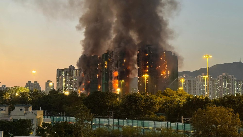 Thick smoke and flames rise as a major fire engulfs several apartment blocks at Wang Fuk Court in Hong Kong's Tai Po district on November 26, 2025. Four people died after multiple blocks in a Hong Kong residential estate went up in flames on November 26, with local media earlier reporting that some residents were trapped.
