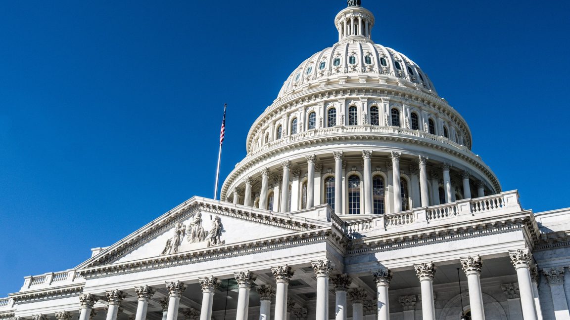 The dome of the United State Capitol Building against a deep blue sky in Washington, DC.