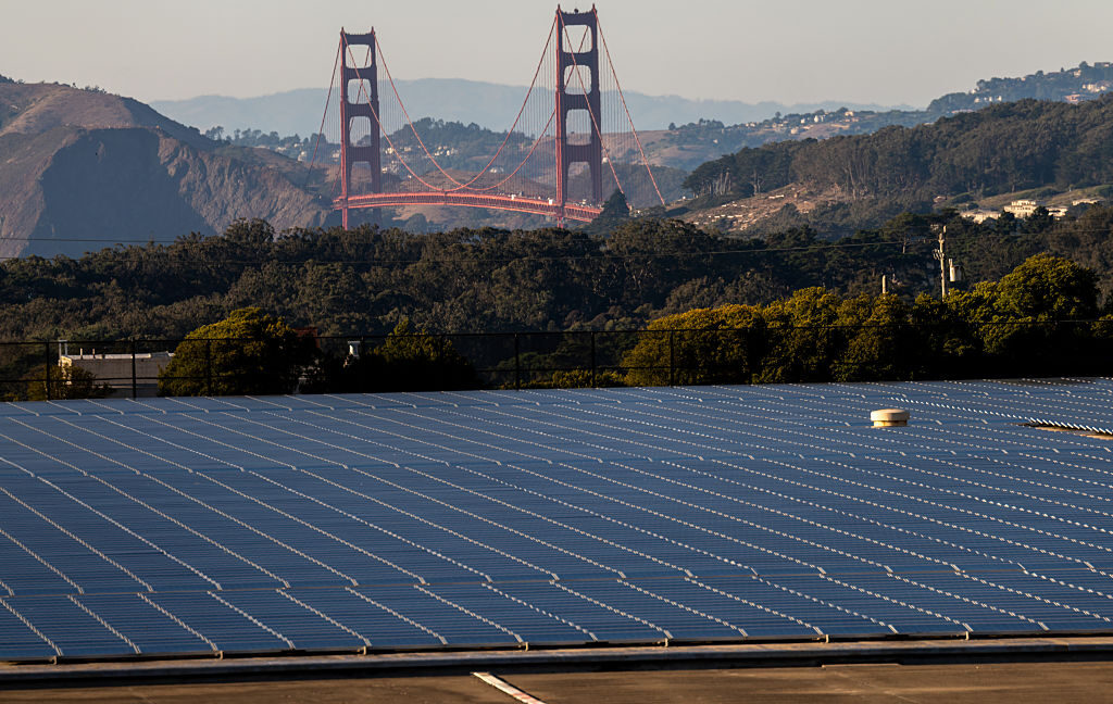 A hillside covered in solar panels, with the Golden Gate Bridge visible in the background.