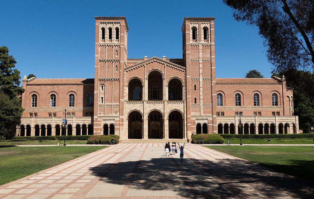 Image of a red brick building at the end of a pathway on a grassy campus.