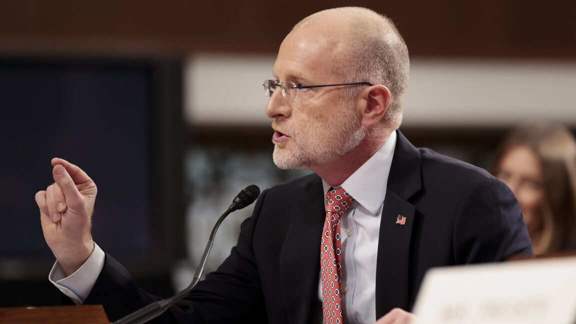 FCC Chairman Brendan Carr sits at a table and points with his hand while testifying at a Senate committee hearing.