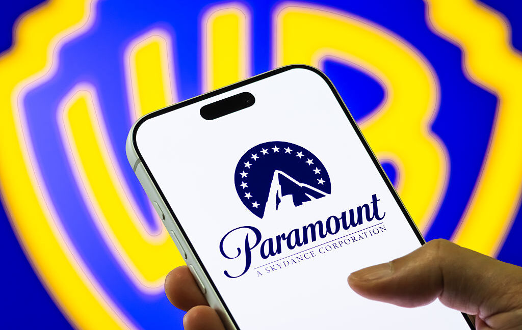 In this photo illustration, a smartphone displays the Paramount Skydance logo in front of a blurred Warner Bros. Discovery emblem, on December 6, 2025.