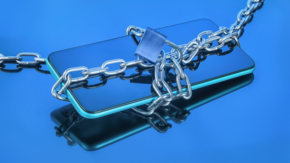 A smartphone wrapped in a metal chain and padlock